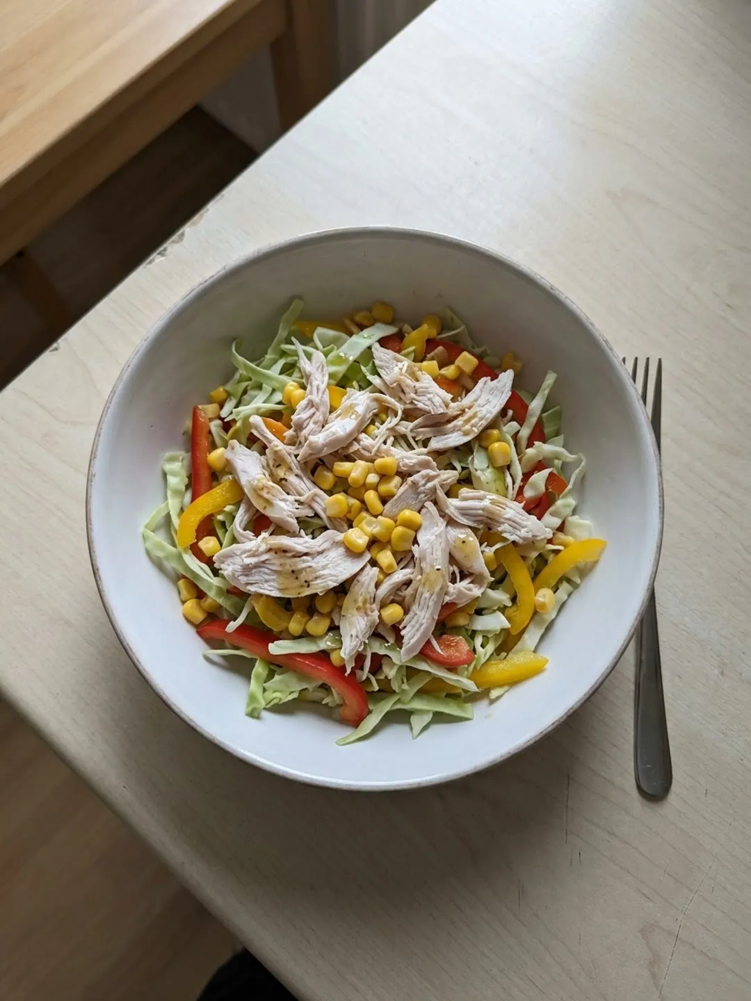 A bowl of shredded chicken, peppers, cabbage and sweetcorn with vinaigrette